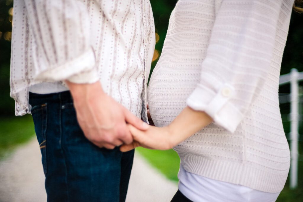 lower body of pregnant couple holding hands