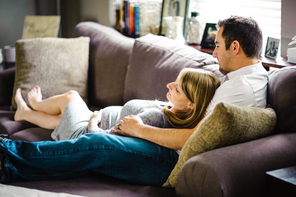 pregnant husband and wife laying on sofa