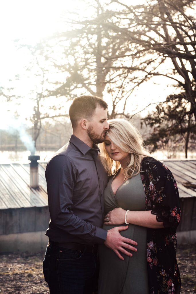 pregnant couple in woods with smoke stack
