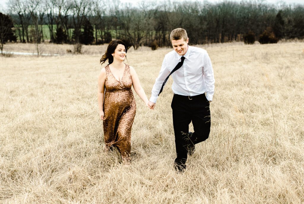pregnant couple walking through winter field