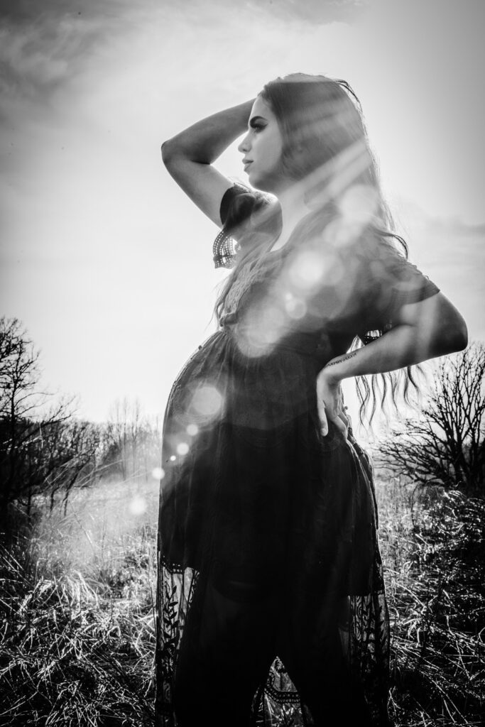 pregnant woman posing in field with sun flare
