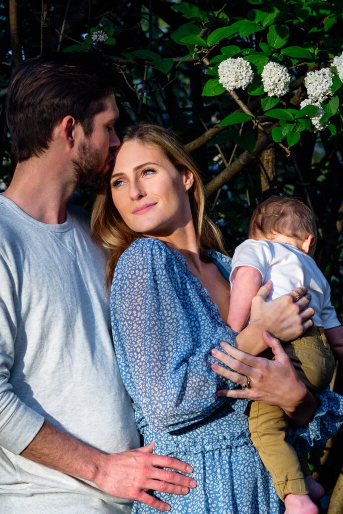 husband kisses wife on forehead in the sunshine