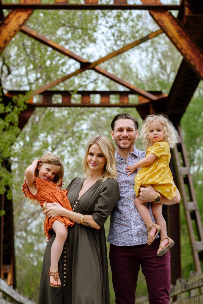 Family of four smile on old railroad bridge