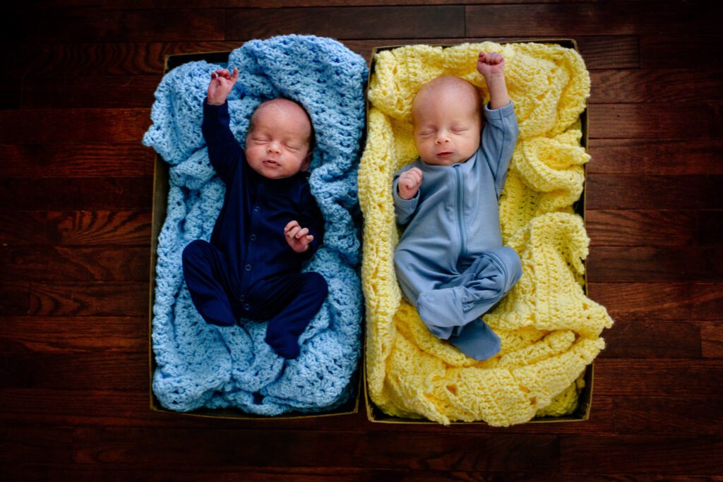 Twin newborn brothers lay on blue and yellow blankets