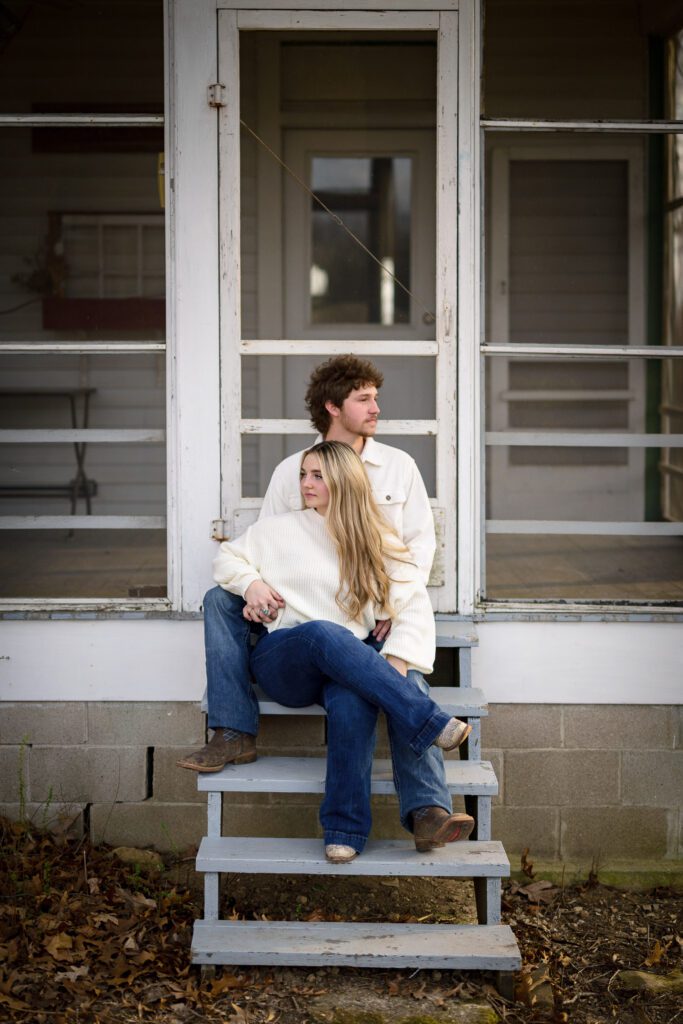 young engaged couple blonde girl sitting on farm house front porch