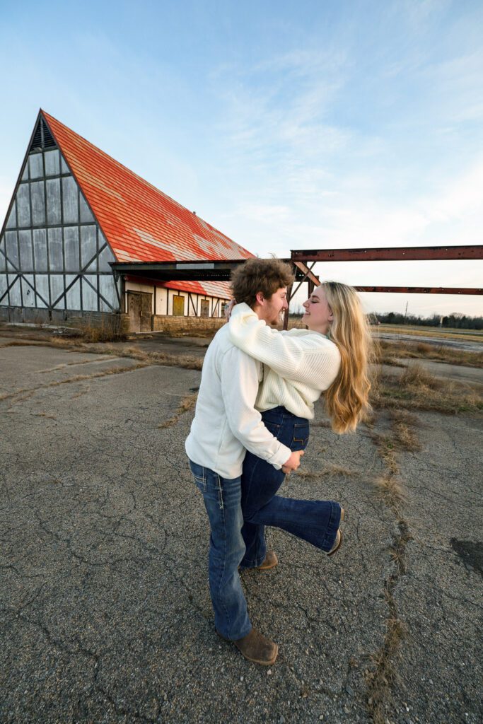 young couple dancing in front of old building with orange roof