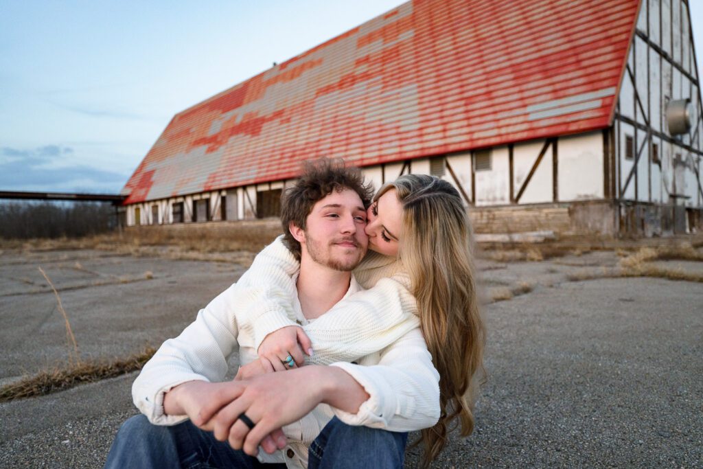 young couple kissing in front of old building with orange roof