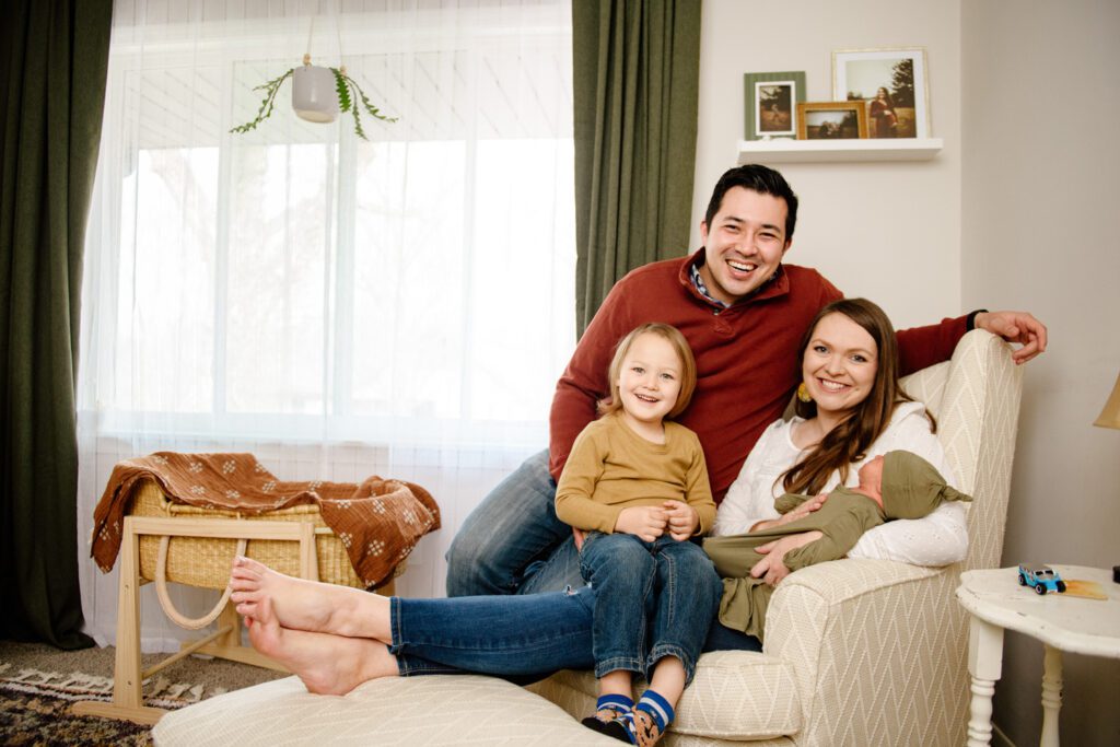 family with newborn sitting in nursery
