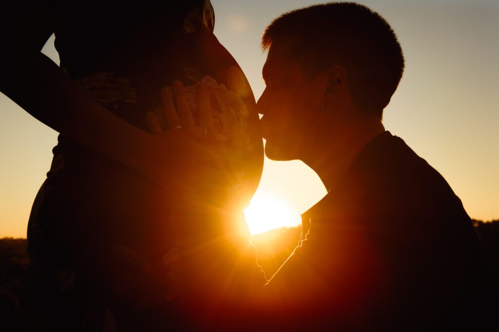 guy kissing woman's pregnant belly
