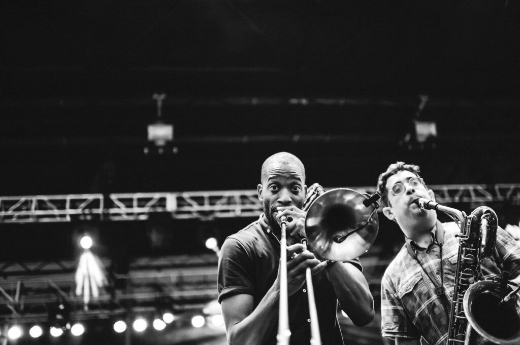 Trombone Shorty looking into camera while playing on stage