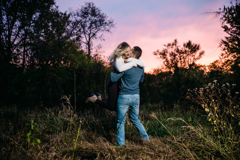 Guy lifts girl at sunset