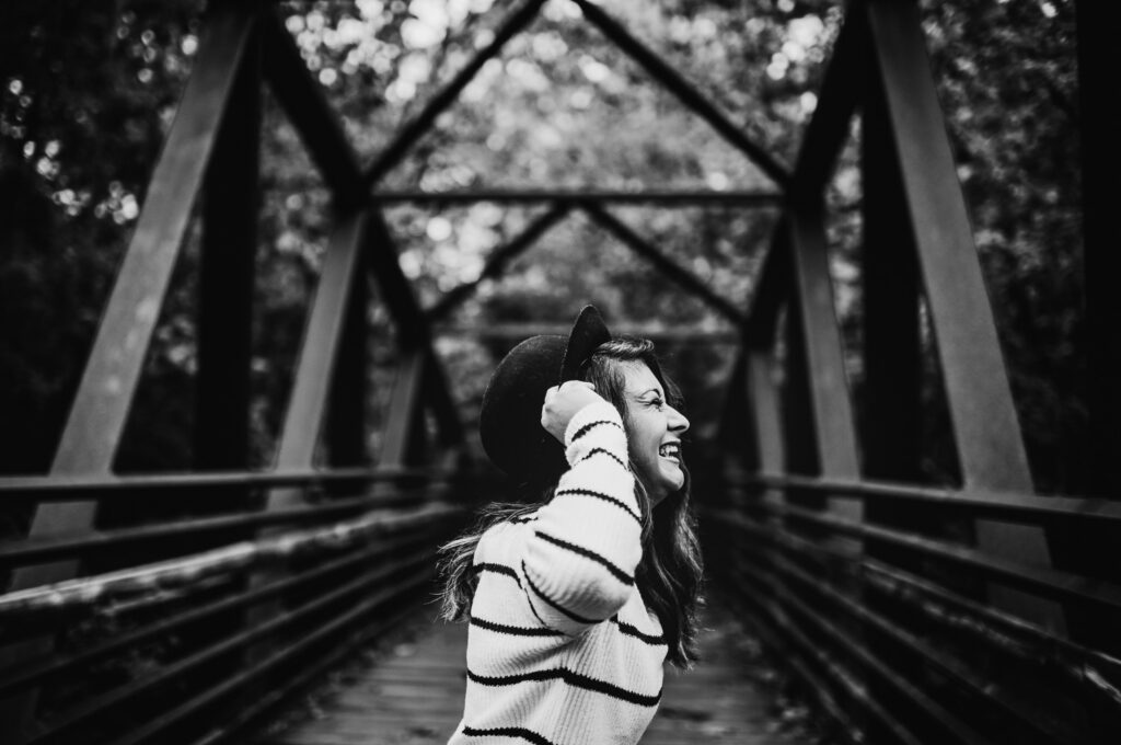 senior girl laughs playing with hat