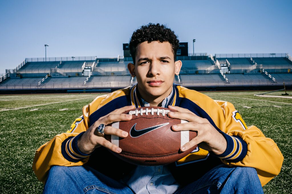 senior holding football on field