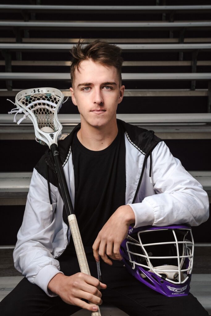 senior guy posing with lacross gear