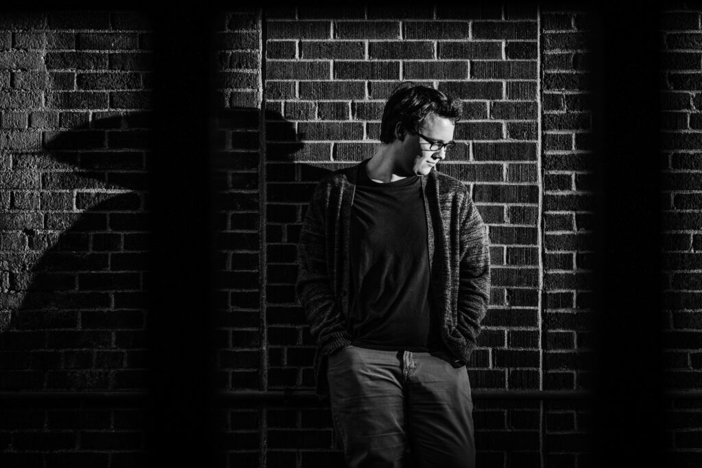 senior looking down up against brick wall