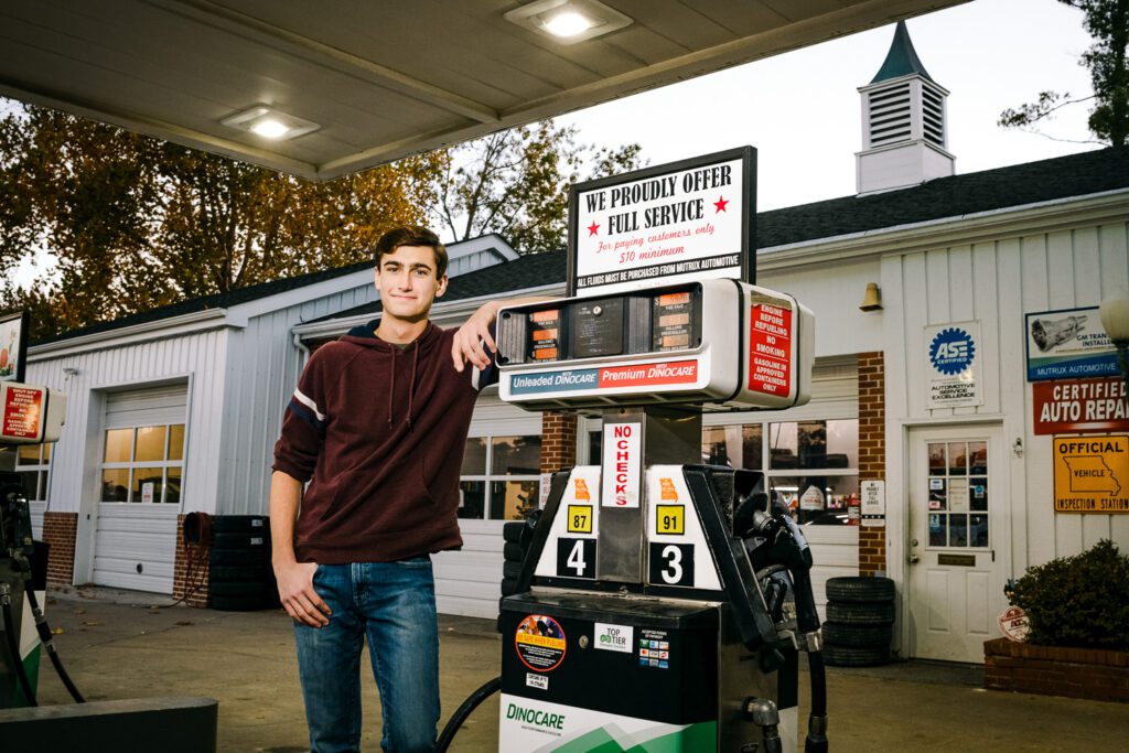 senior guy leans on gas pump