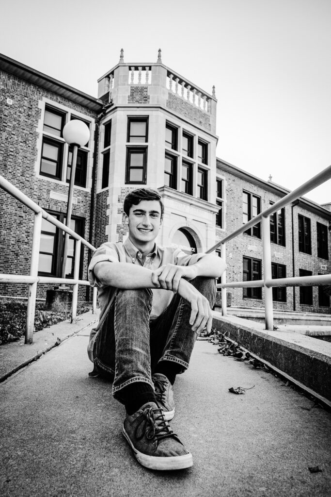 senior guy sits in front of Hichman High School