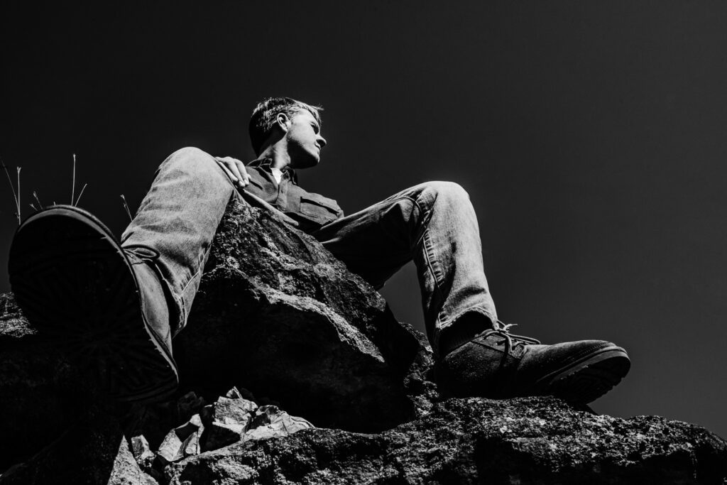 senior guy sitting on giant rock