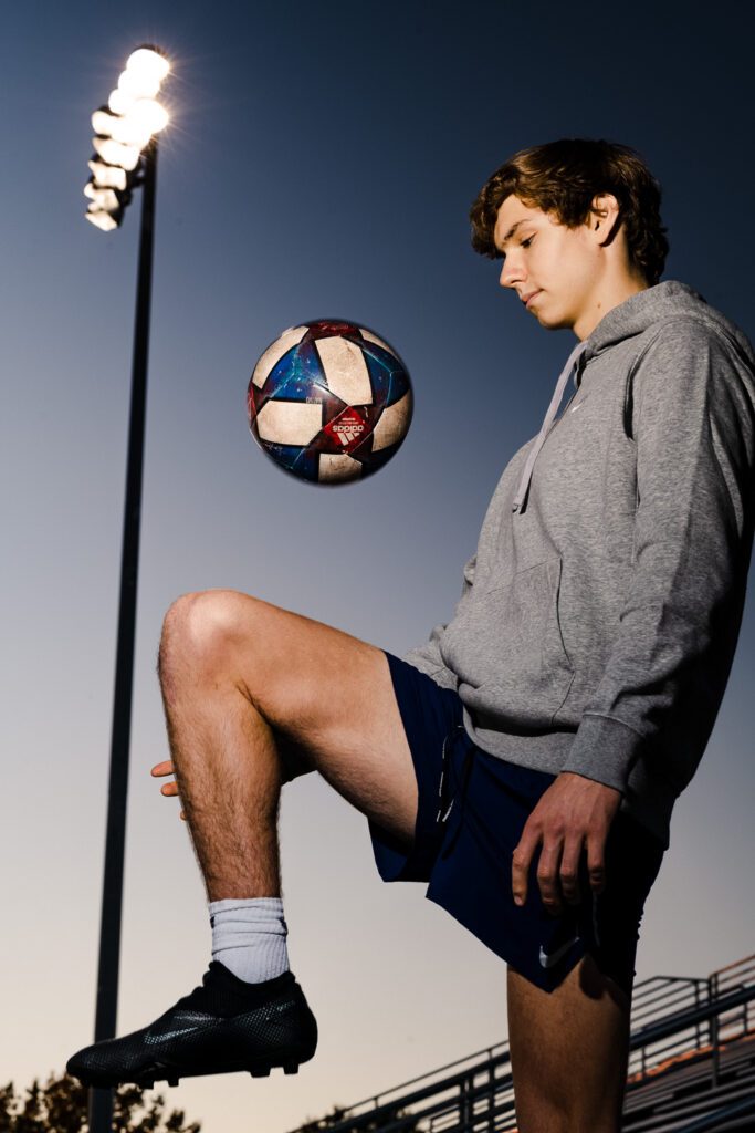 senior guy bounces soccer ball on knee