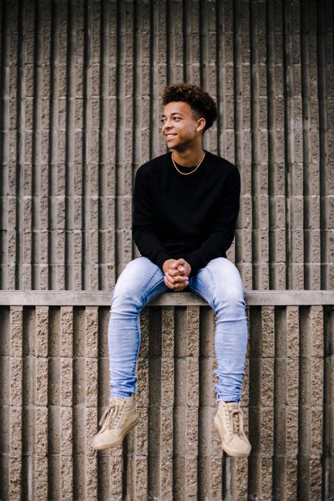 senior guy sitting in front of textured wall