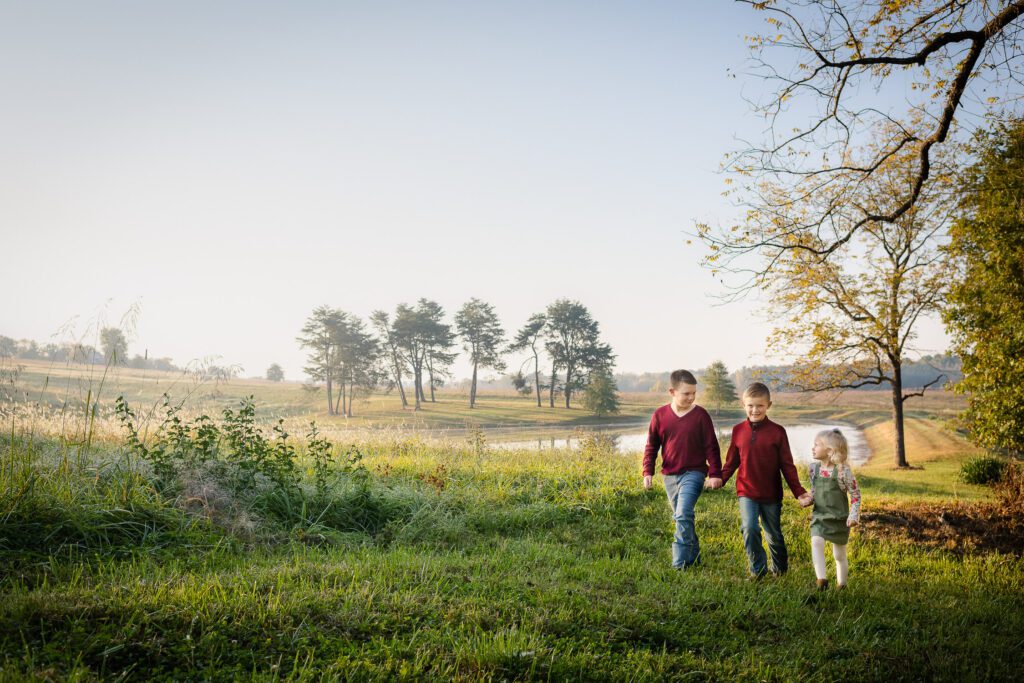 siblings walking in front of foggy pond at farm in Columbia, MO