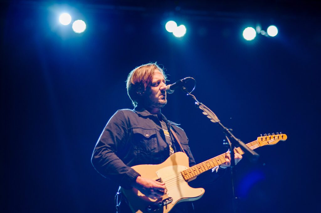 Sturgill Simpson playing guitar under blue lights