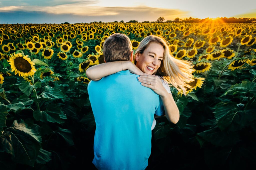 swinging engagement couple in front of sunflower field