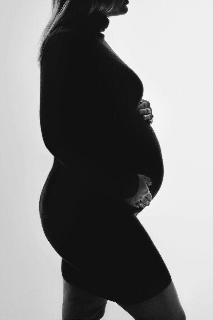 pregnant woman holding belly wearing turtleneck dress