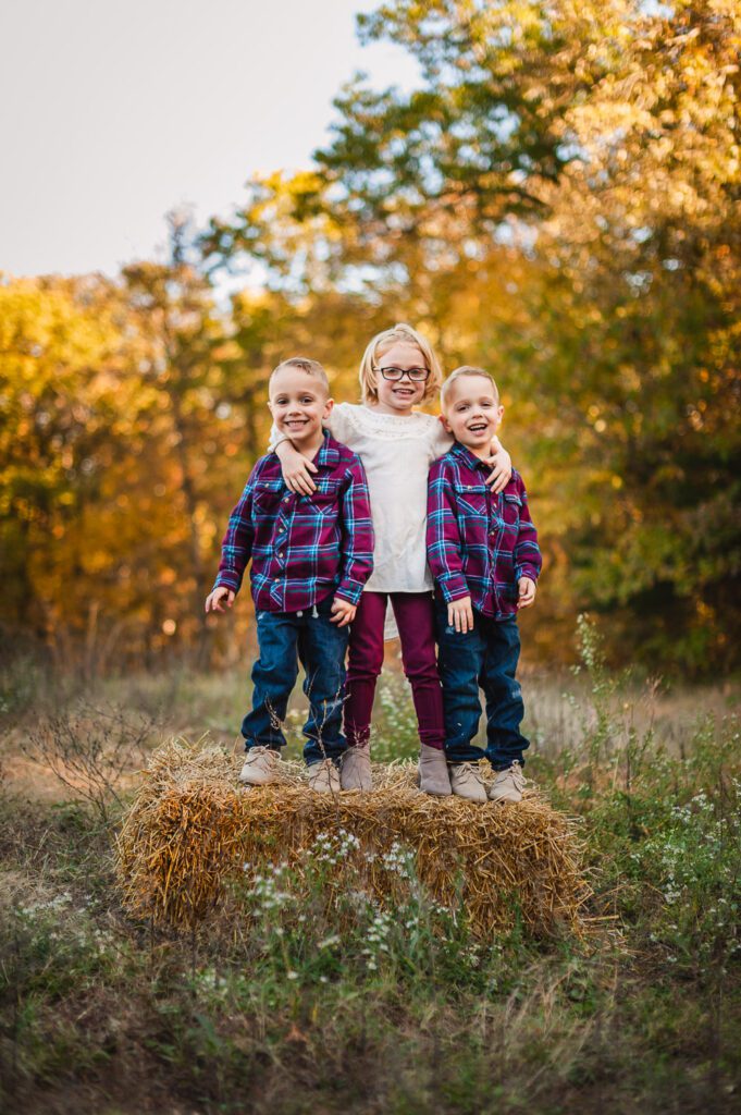 twins with big sister on a hay bale