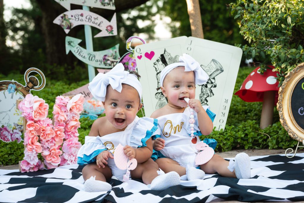 twin sisters smiling Alice in Wonderland themed cake smash Shelter Gardens, Columbia, MO