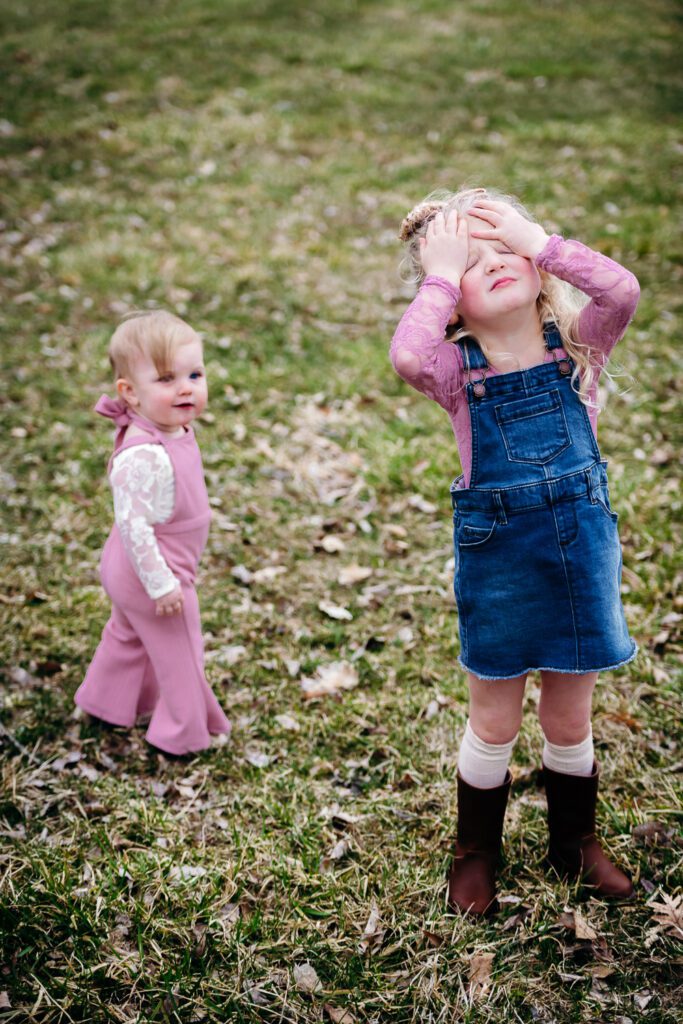 big sister covering her eyes near little sister