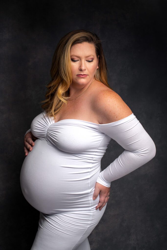 pregnant woman posing in white maternity dress
