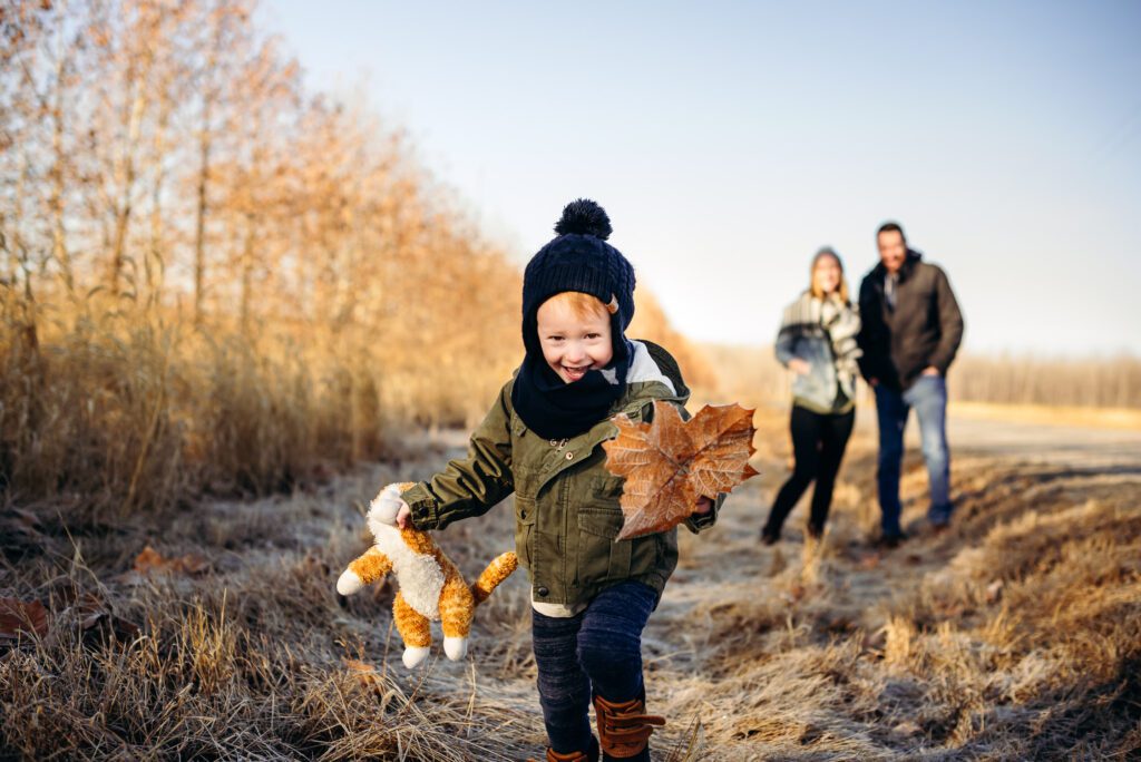 boy wearing winter hat and carrying stuffed cat toy