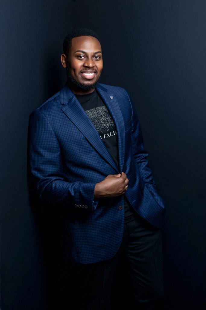 black male model leaning on black wall wearing armani tshirt and blue blazer