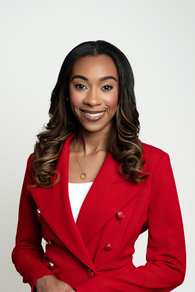 black female with brown hair wearing red blazer