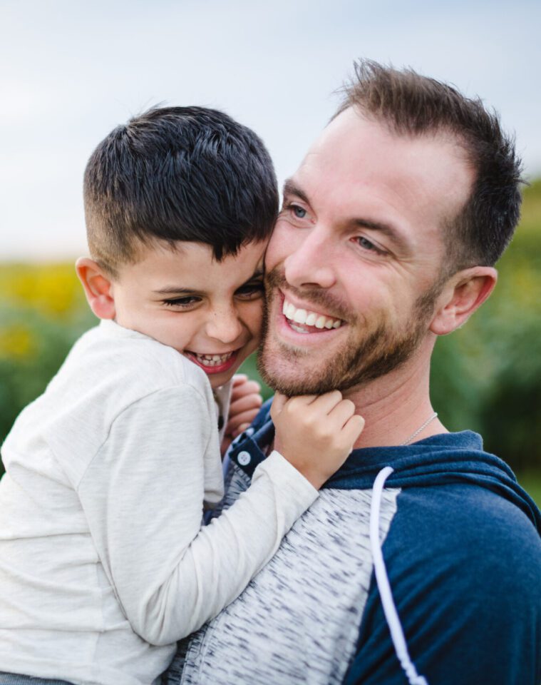 father and son smiling in front of sunflower field in Columbia, MO
