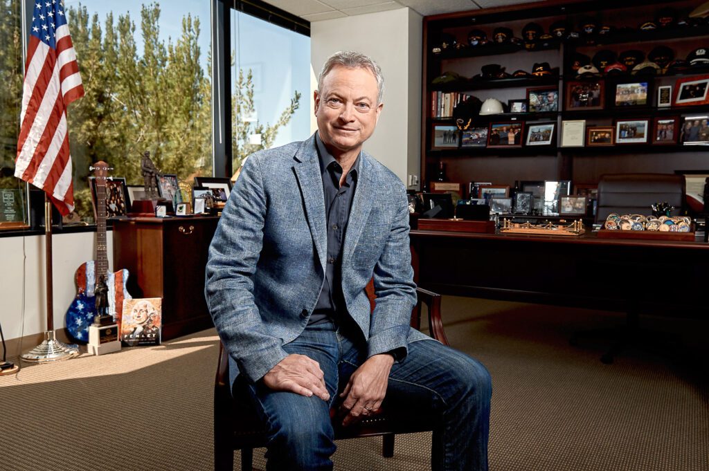 Actor Gary Sinise wearing blue jacket sitting in office
