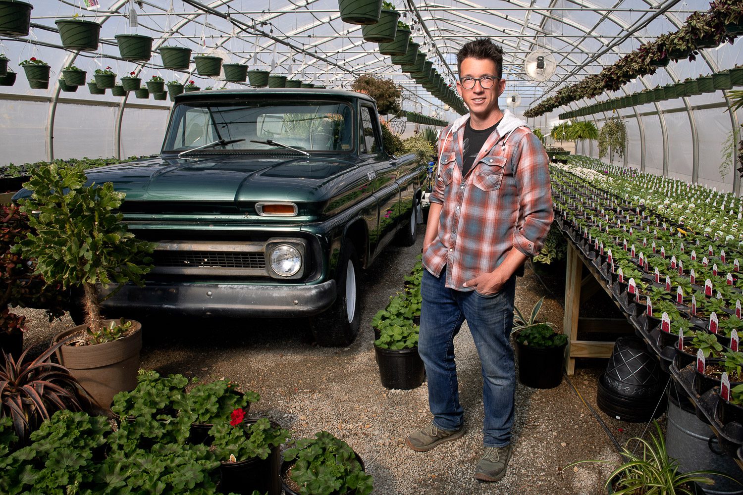 Greenhouse owner stands by old green truck in Callaway Fields Greenhouse