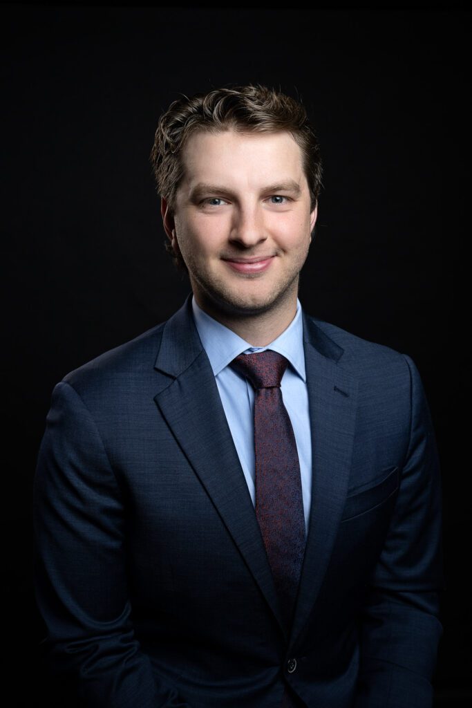 male in blue suit for business corporate headshot with black background