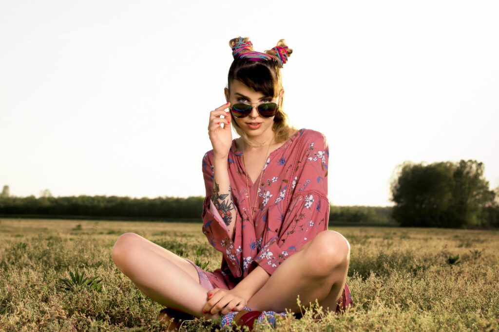 Model with space buns sitting in field