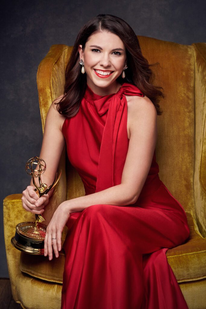 Female model wearing red evening gown holding emmy award