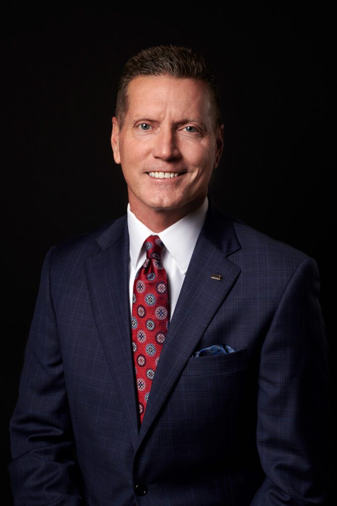 guy wearing navy suit and red tie business headshot on black background