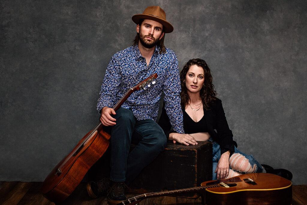 couple sit by two guitars