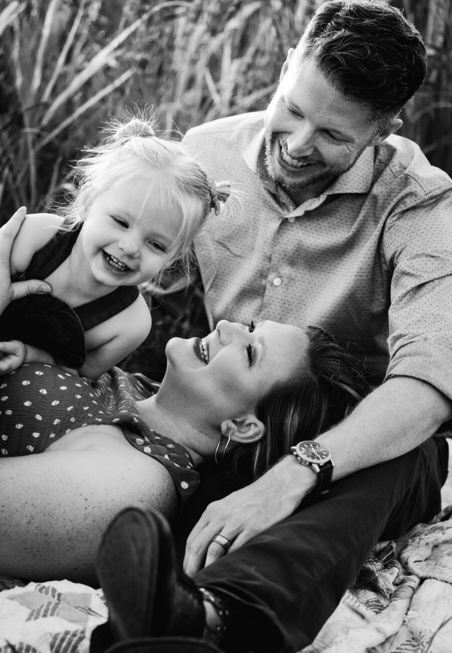 husband and wife laughing with daughter