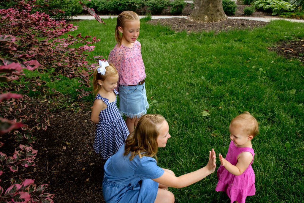 Two girls high five while other sisters look on.