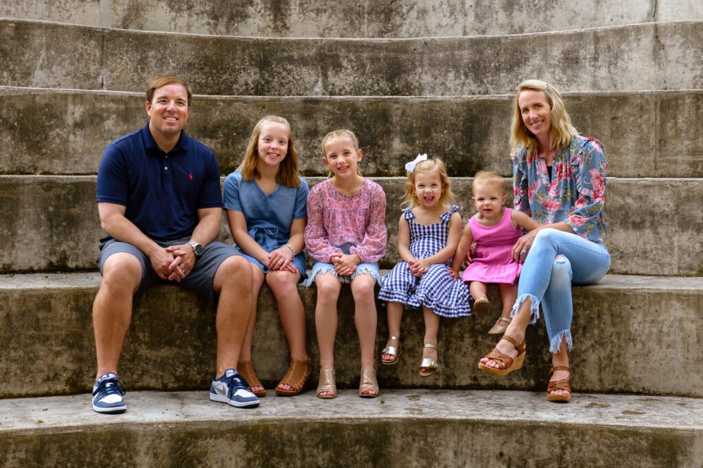 The Eli Drinkwitz family sits next to each other on a concrete step near the Missouri School of Journalism.