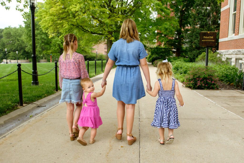 One sister looks back while holding her older sister's hands.