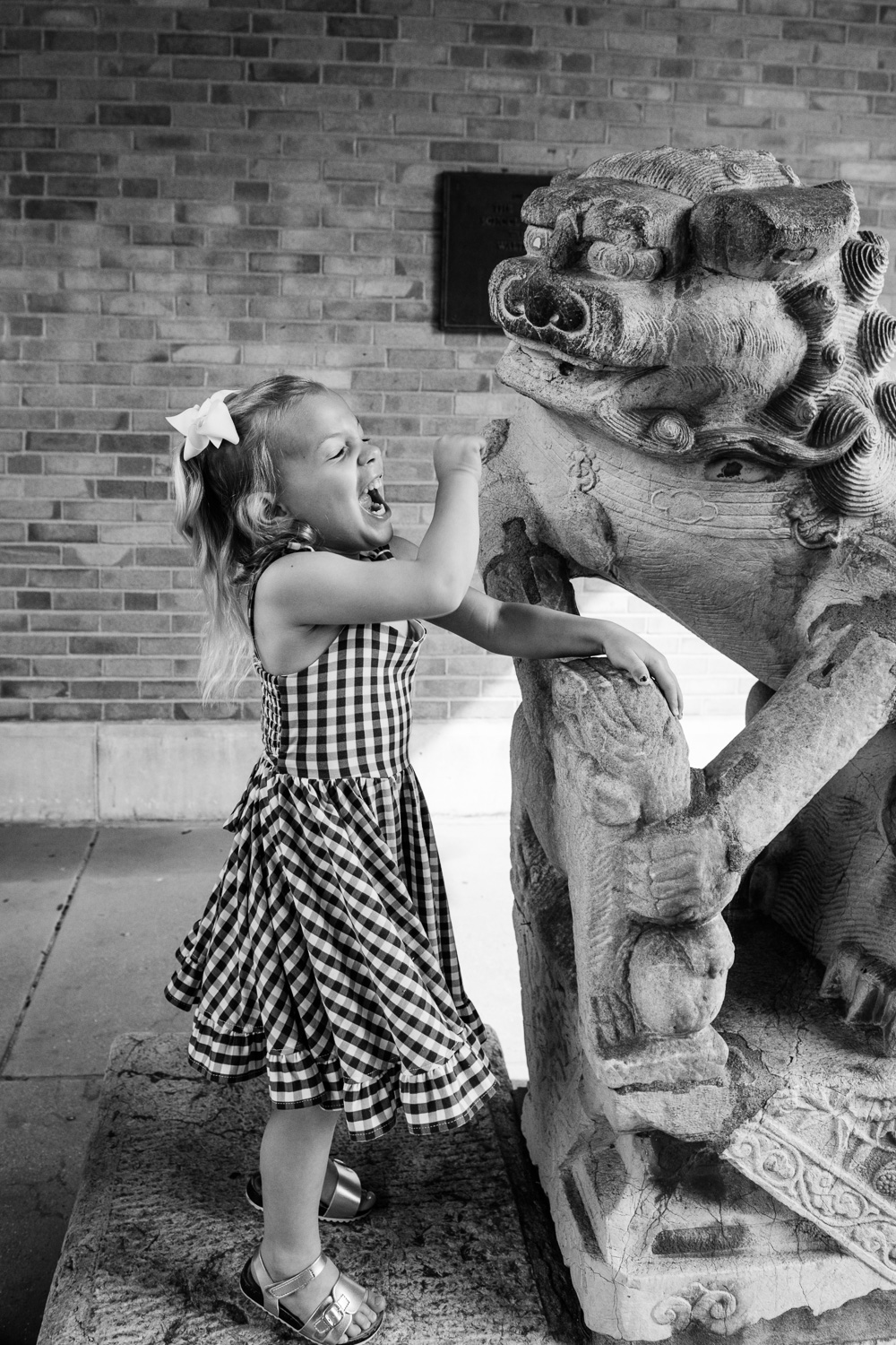 Young girl roars like a tiger by an Ancient Chinese Lion at the Missouri School of Journalism.