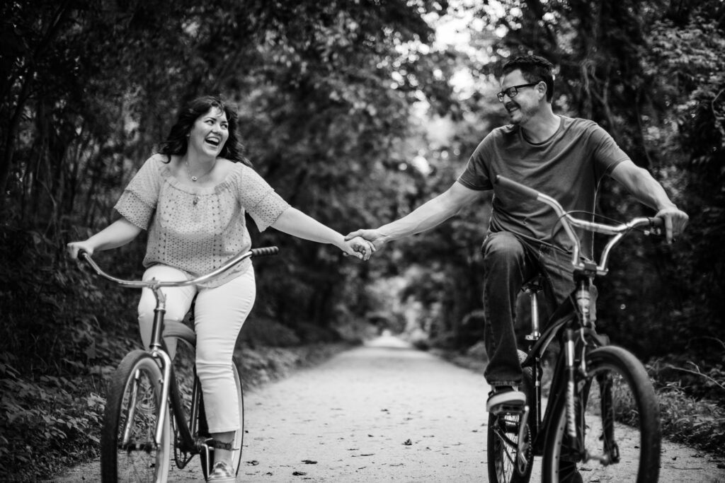 Couple hold hands while riding bikes
