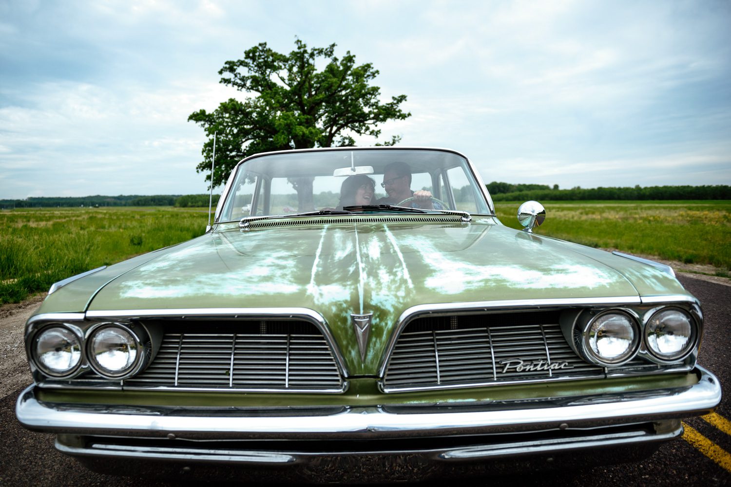 Engaged couple inside green 1961 pontiac catalina